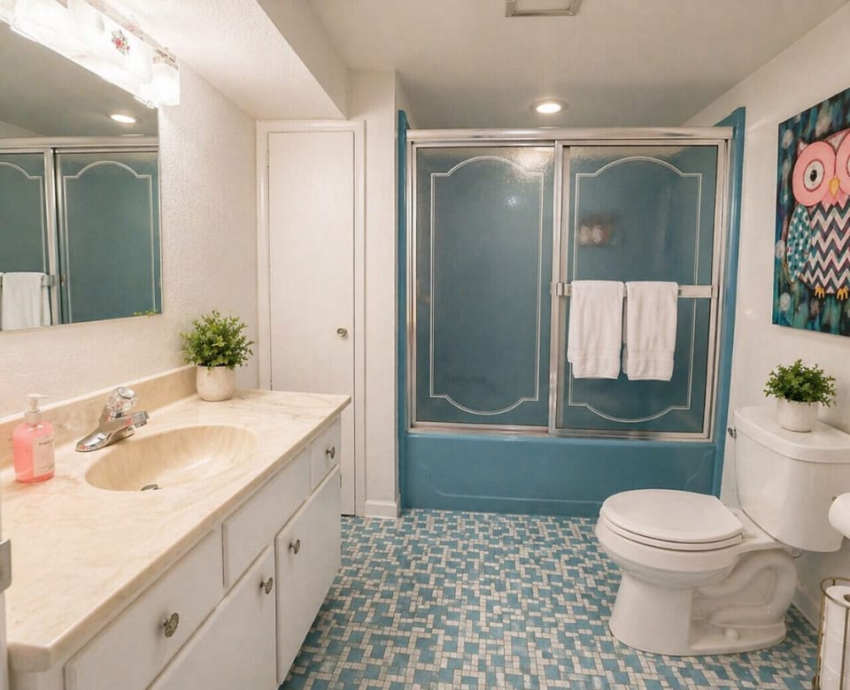 Bright and spacious bathroom with tub/shower combo and ample vanity space—perfect for family-friendly stays, comfort, and everyday convenience.