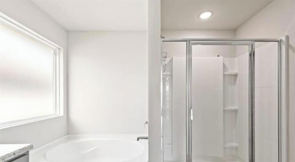 master bathroom with double sink, bathtub, shower, toilet, and walk in closet