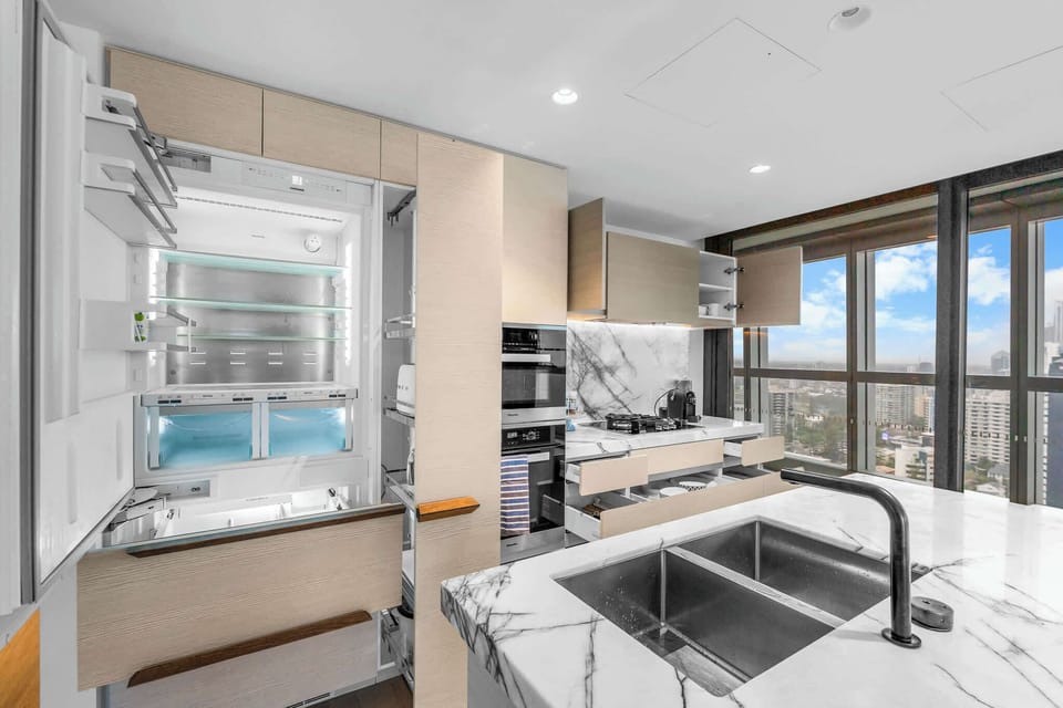 Modern kitchen with marble island bench, integrated appliances and city skyline outlooks.