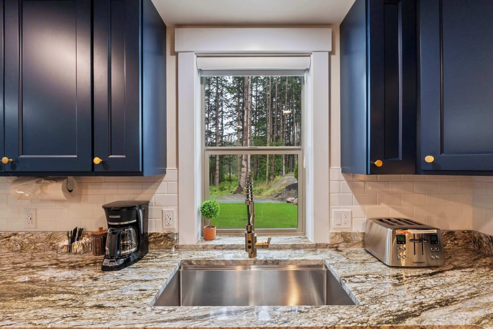 Do the dishes with a view—bright, airy sink space facing lush outdoor scenery.