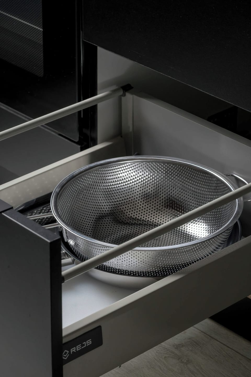 Close-up of neatly stored kitchen equipment inside a modern built-in cabinet drawer.