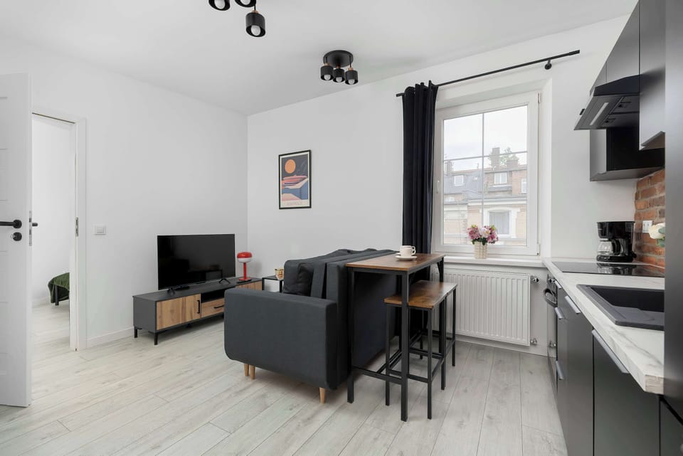 Minimalist living room with a TV, dining table, and open kitchen layout.