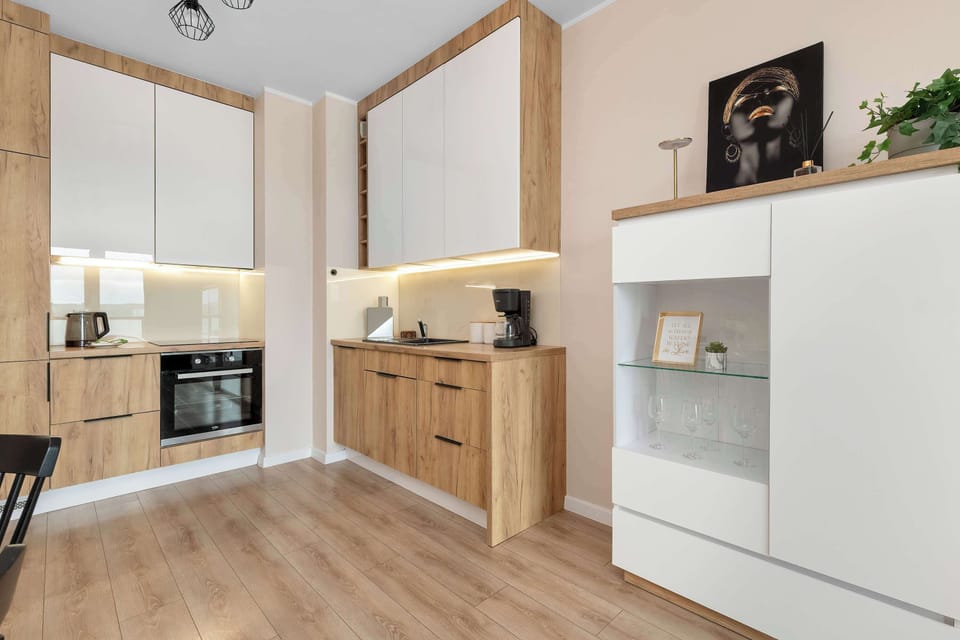 A wider perspective of the kitchen reveals a tall white cabinet unit that offers extra storage space. The seamless transition between the white and wood finishes maintains a cohesive look.
