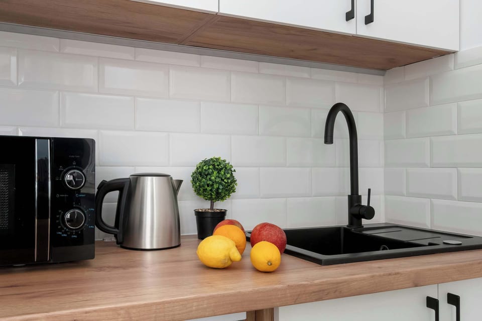 A close-up view of the kitchen workspace with a sink, coffee machine, and fresh fruit on the counter. The area looks practical and stylish for everyday use.