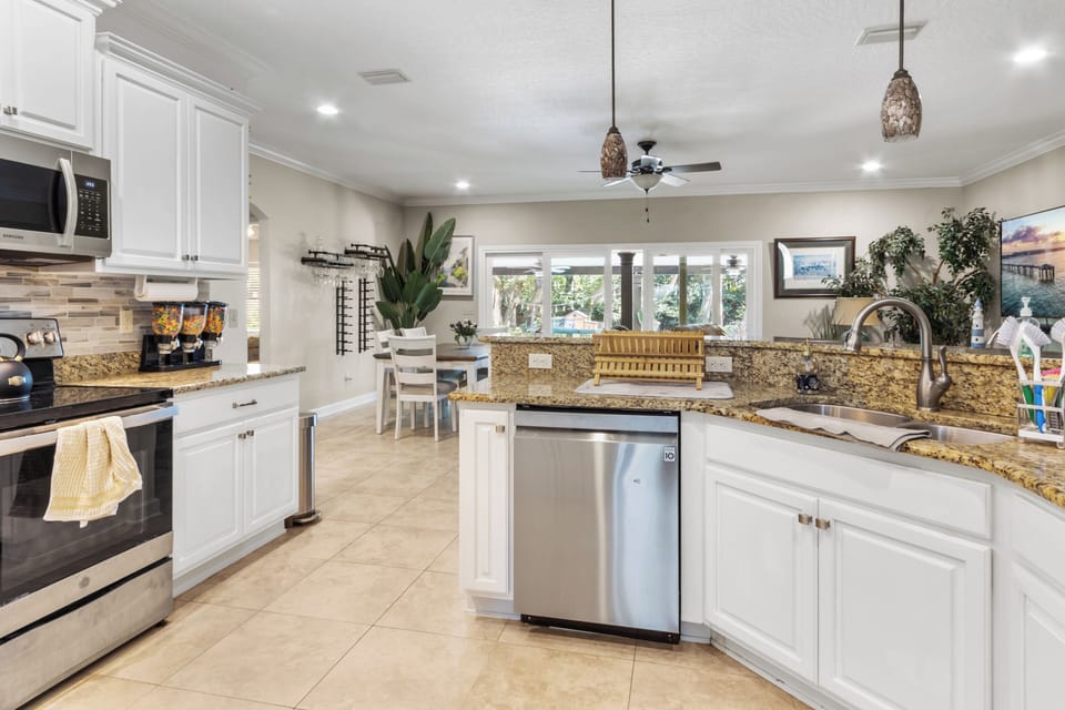 Bright kitchen with white cabinets, granite countertops, and a seamless view into the sunlit dining area.