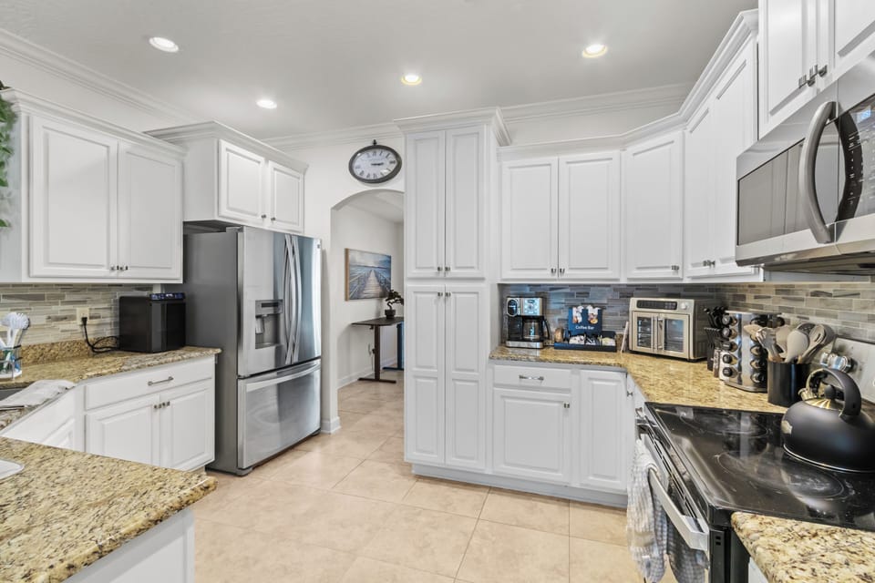 Spacious kitchen featuring white cabinetry, granite countertops, and stainless steel appliances.