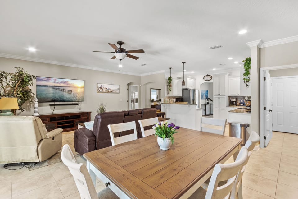 Open-concept dining and living area with a rustic wood table, modern kitchen, and abundant natural light.