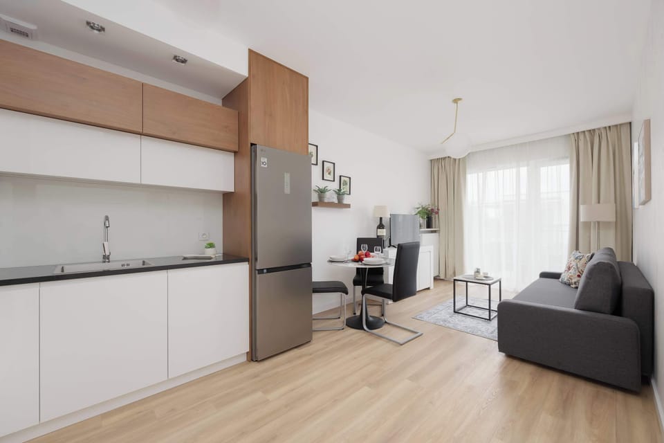 A modern kitchenette with white cabinets and wooden accents connected to the living area. The bright interior looks clean and functional.