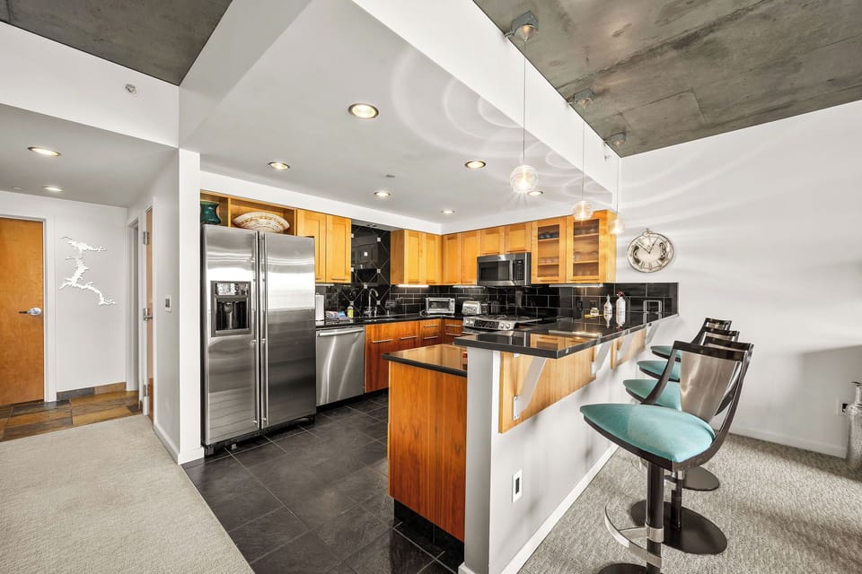Whip up your favorite meals in this sleek, fully-equipped kitchen with stainless steel appliances, ample counter space, and modern bar seating for casual dining.