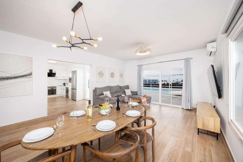 Open-plan living room with sofa, dining area, kitchen, A/C, WiFi internet, and satellite TV