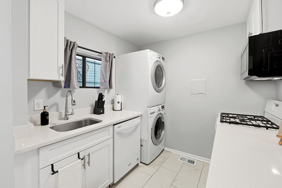 Bright modern laundry room with stacked washer/dryer and sleek finishes
