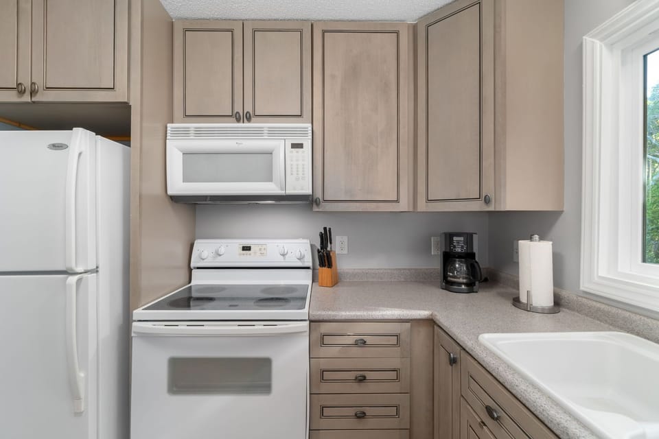 Clean, modern kitchen with a glass-top range, spacious sink, and both a drip coffee maker and Keurig—perfect for easy mornings at the beach. Bright, functional space in this Pine Knoll Shores condo on Bogue Banks, near Emerald Isle and Atlantic Beach.