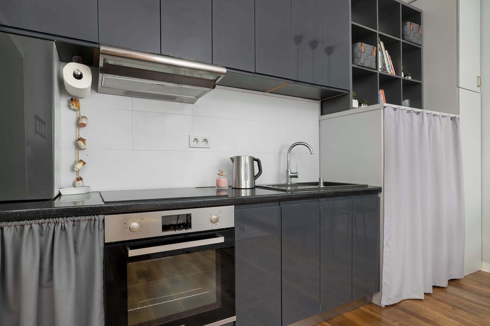 A modern kitchenette with dark cabinets and built-in appliances. The minimalist design gives the space a clean and elegant feel.