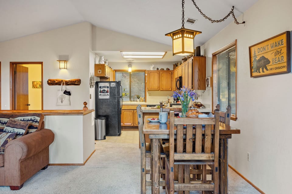 Rustic cabin dining and kitchen area with warm wood details, cozy lighting, and charming mountain-inspired decor.