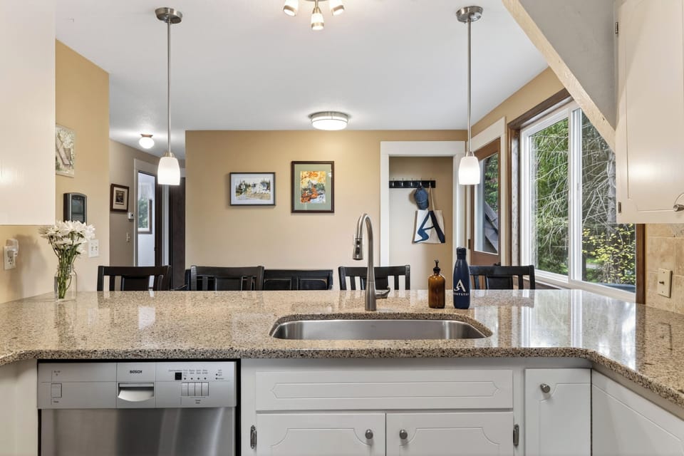 A bright, well-equipped kitchen with breakfast bar seating and peaceful views from the window.