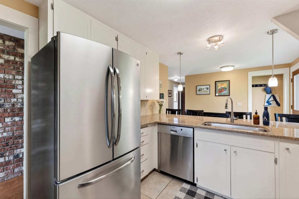 A bright, well-equipped kitchen with breakfast bar seating and peaceful views from the window.