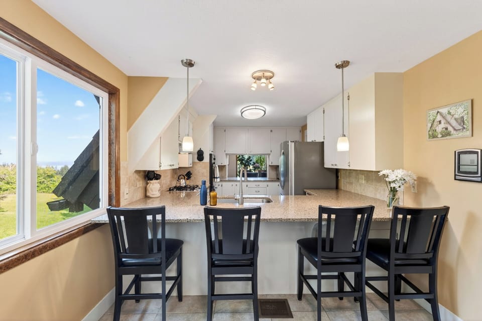A bright, well-equipped kitchen with breakfast bar seating and peaceful views from the window.