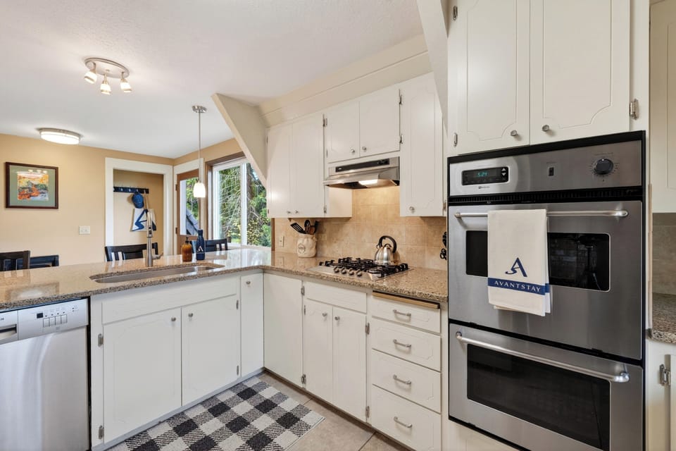 A bright, well-equipped kitchen with breakfast bar seating and peaceful views from the window.
