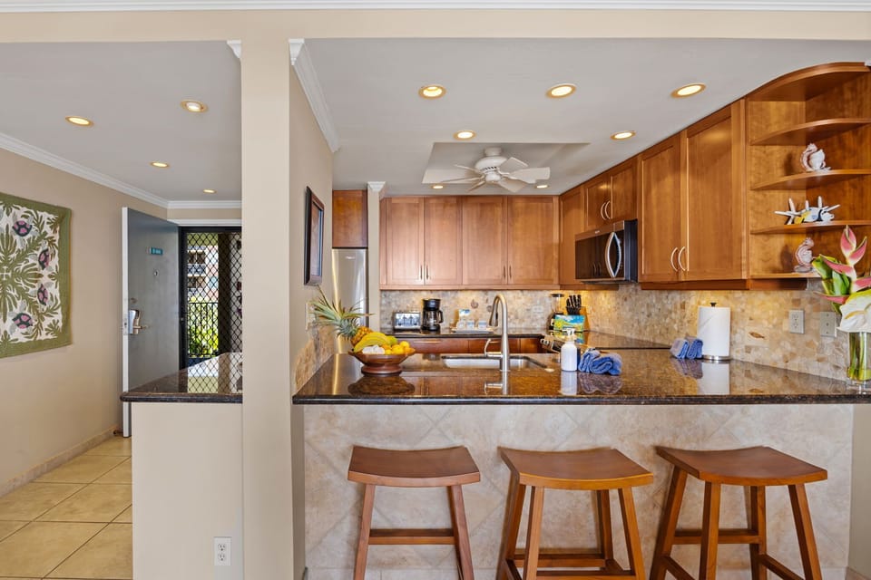 Kitchen - Prepare meals in the fully equipped kitchen featuring warm wood cabinetry, granite countertops, stainless steel appliances, and a convenient breakfast bar with counter sitting