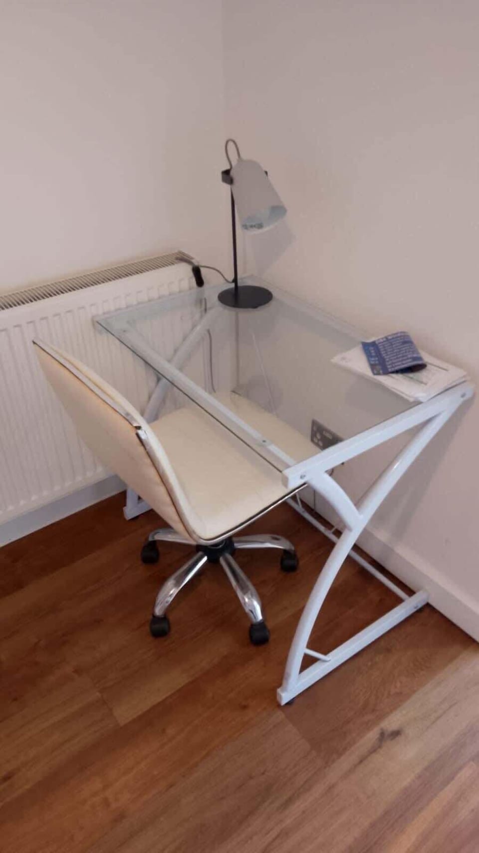 Modern study corner with a sleek glass desk, ergonomic chair, and task lamp, ideal for work or study