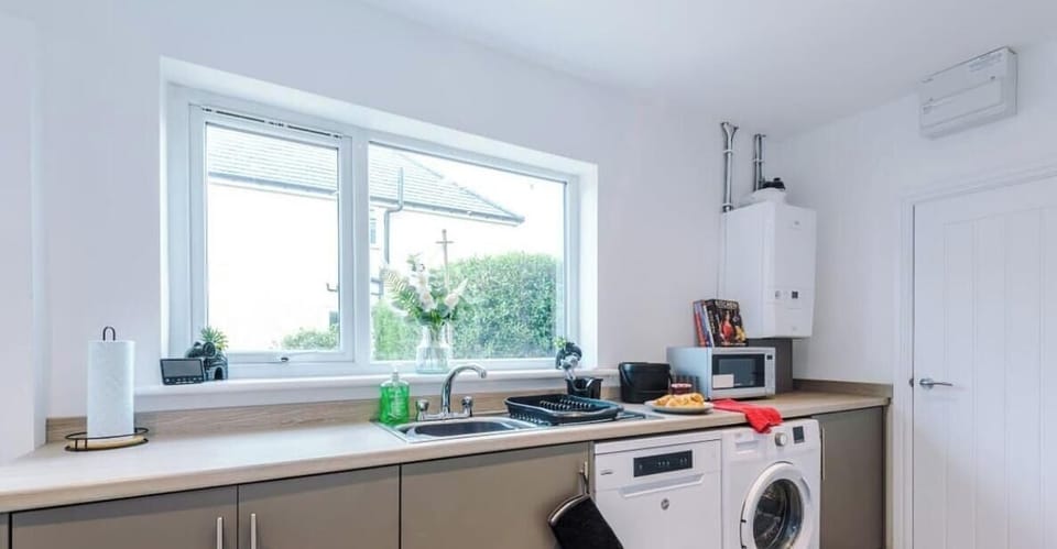 A bright and modern kitchen with sleek grey cabinets and wood-effect flooring.
Fully equipped with oven, microwave, washing machine, and dishwasher.
Large windows and a breakfast bar create a fresh, welcoming space to dine or relax.