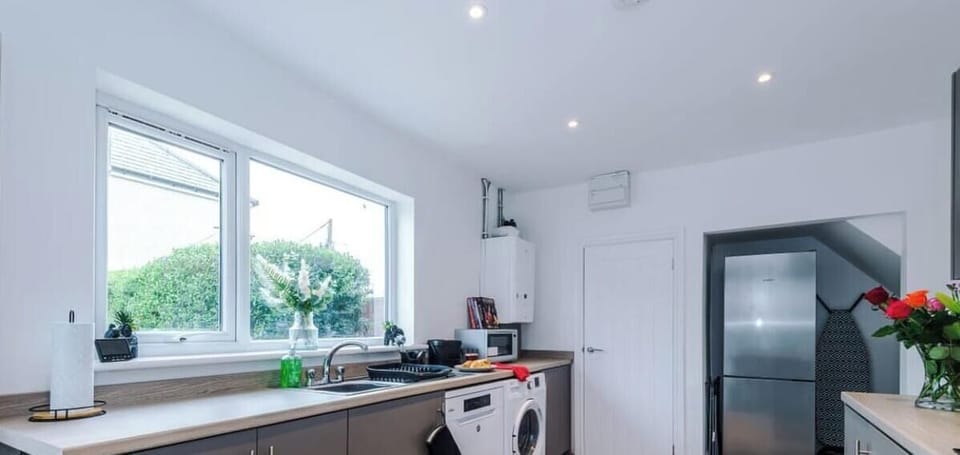 A bright and modern kitchen with sleek grey cabinets and wood-effect flooring.
Fully equipped with oven, microwave, washing machine, and dishwasher.
Large windows and a breakfast bar create a fresh, welcoming space to dine or relax.