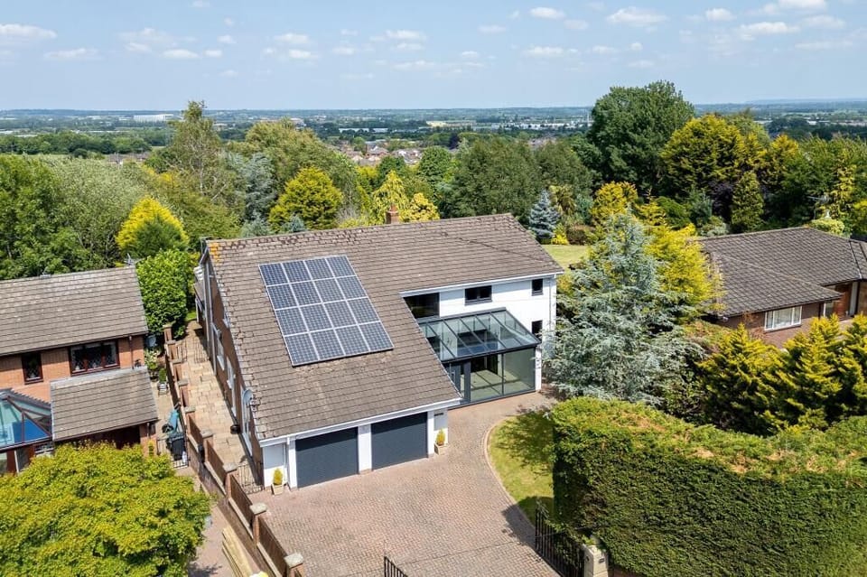 This impressive modern home stands out with its solar-panel roof, double garage, and expansive driveway offering plenty of private parking. Surrounded by mature trees and landscaped gardens, the property combines privacy with a serene natural setting