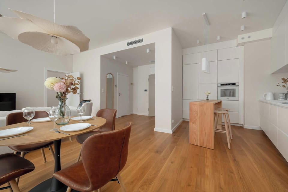 A sleek kitchen with integrated appliances, white cabinets, and wooden countertops. The functional layout offers plenty of workspace for cooking and dining.