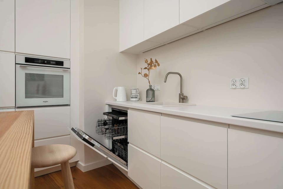 A narrow kitchen layout with built-in appliances, sleek surfaces, and subtle decorative details. Minimalist finishes create a clean and organized appearance.