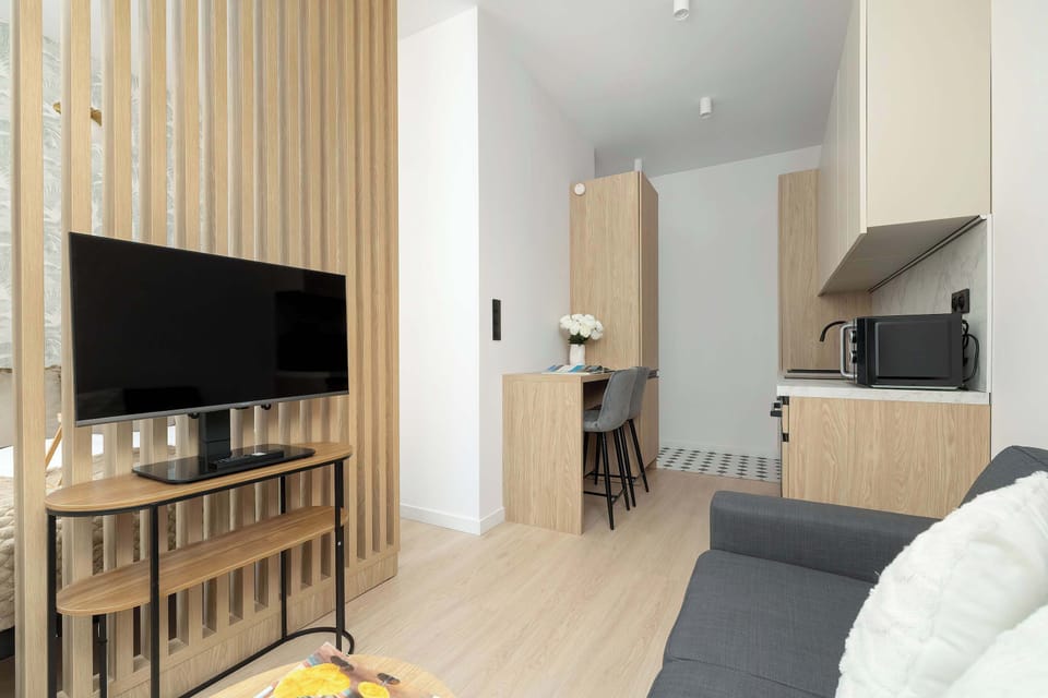 A cozy corner with a sofa and a soft, minimal interior style, continuing the light wood and neutral theme.