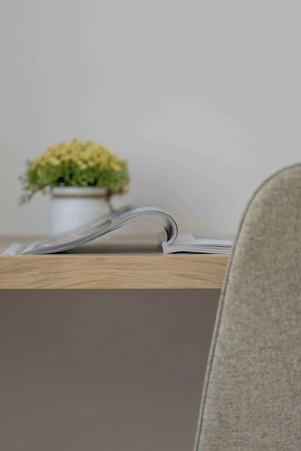 A minimalist workspace detail with a wooden desk, upholstered chair, and subtle decorative accents creating a calm atmosphere.