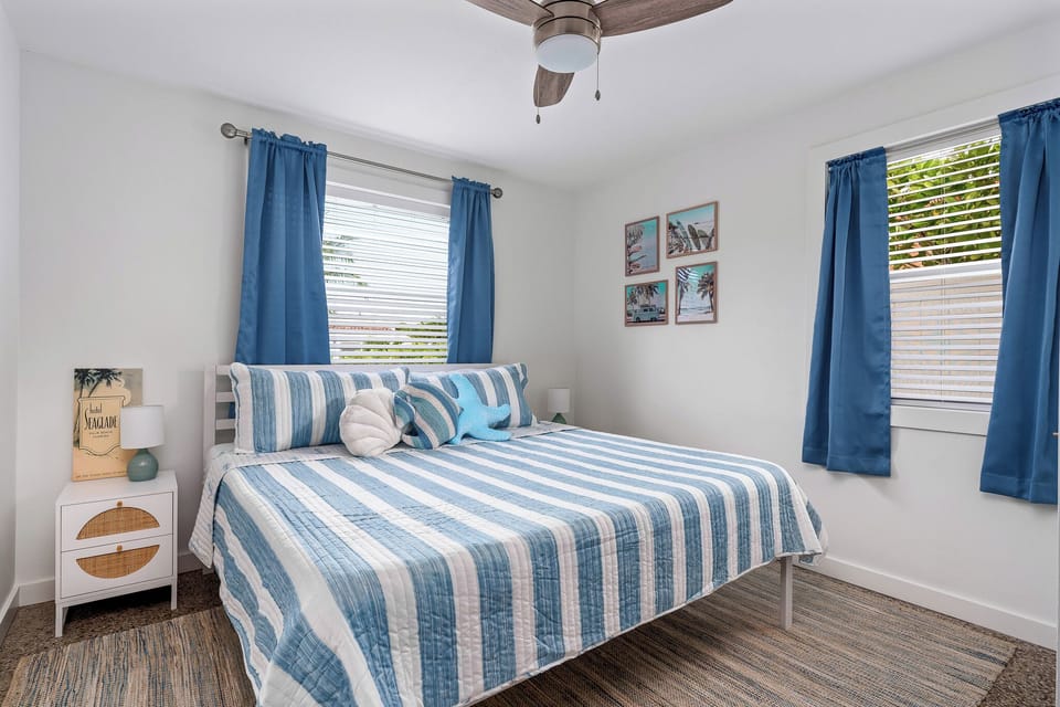 King bed in a spacious primary suite featuring coastal decor and plenty of natural light.