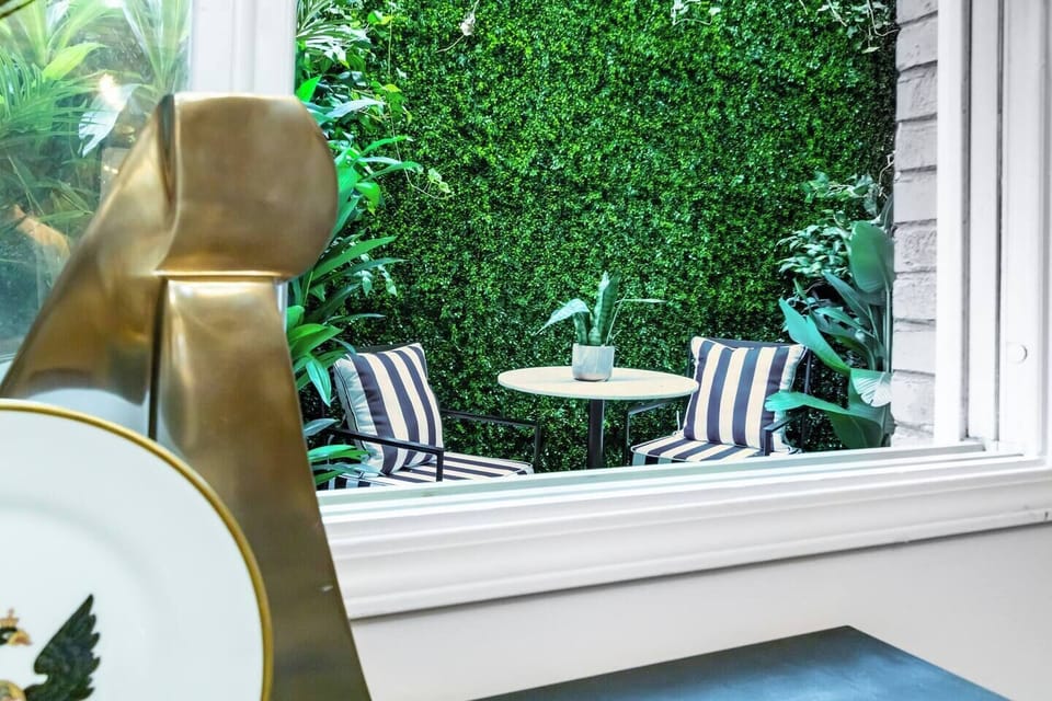 From the comfort of the bedroom, enjoy calming views of the private outdoor seating area surrounded by lush greenery, creating a peaceful indoor-outdoor retreat.