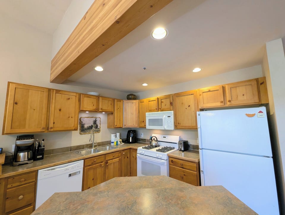 Step into your fully equipped kitchen, where warm wood tones and modern appliances invite you to prepare meals surrounded by rustic charm and modern convenience.