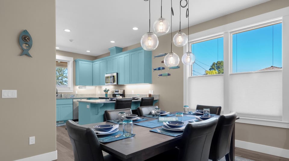 Gather around your stylish dining table beneath stunning pendant lights, with turquoise kitchen cabinets creating a coastal vibe for memorable meals.