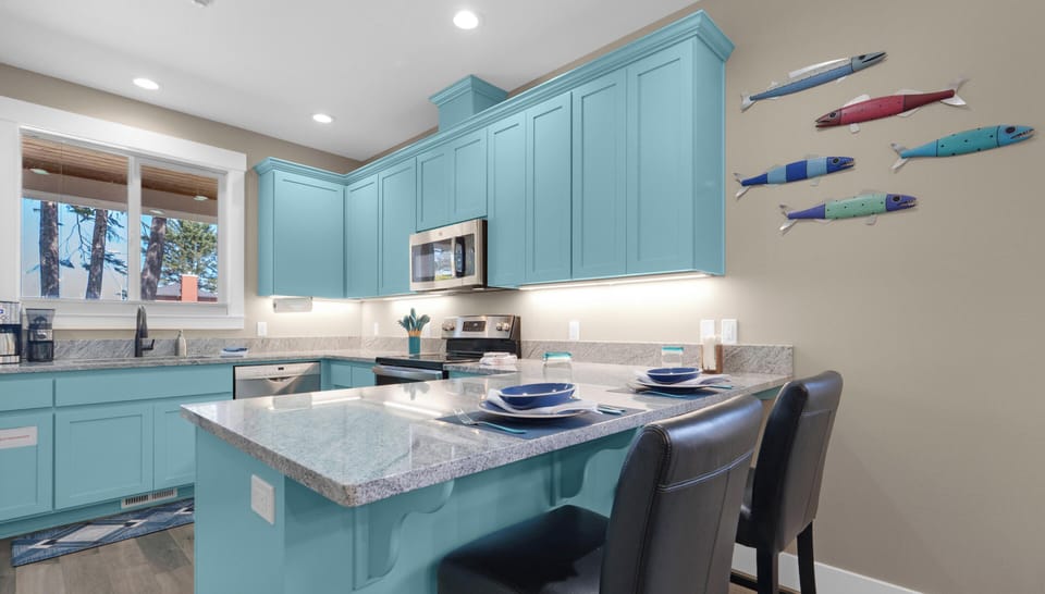 Cook up memories in this bright turquoise kitchen featuring granite countertops, stainless appliances, and playful fish art that sets a coastal mood.