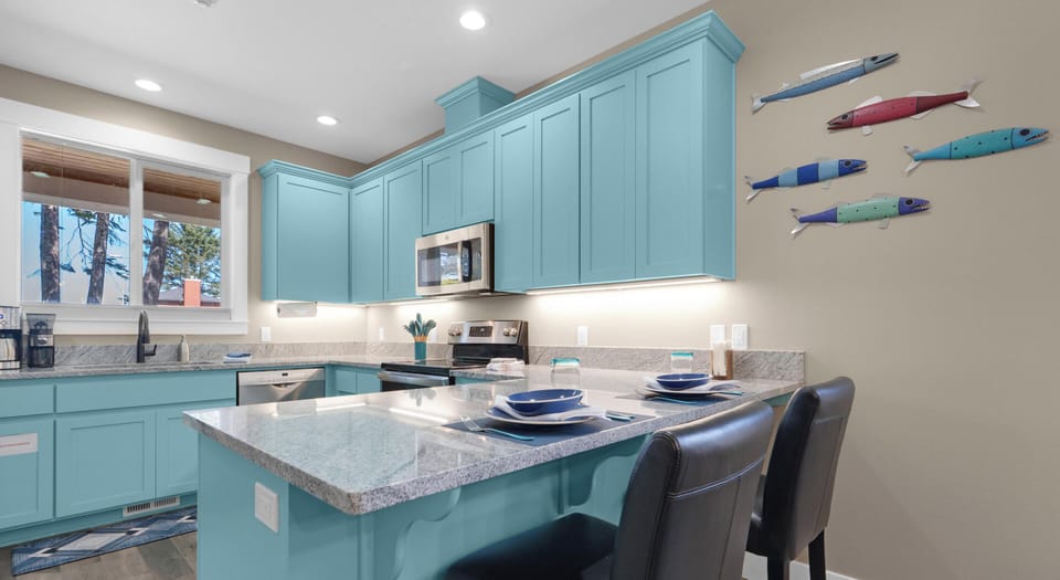 Cook up memories in this bright turquoise kitchen featuring granite countertops, stainless appliances, and playful fish art that sets a coastal mood.