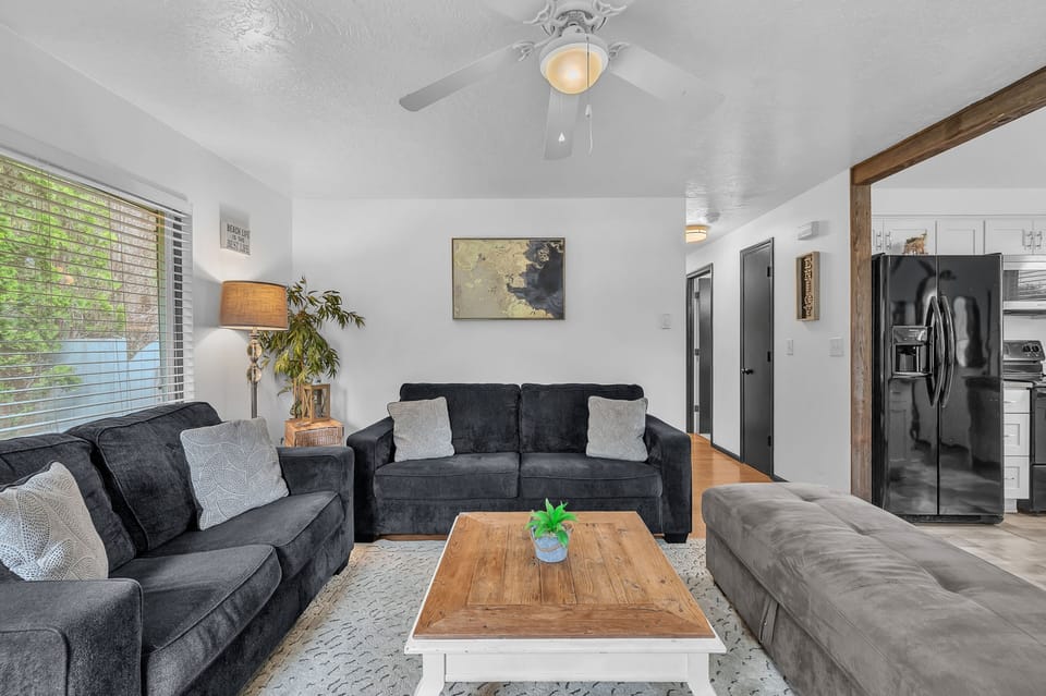 Unwind in this thoughtfully designed living space featuring plush seating, natural light streaming through large windows, and a ceiling fan to keep you comfortable. Modern touches blend seamlessly with cozy furnishings for your perfect retreat.
