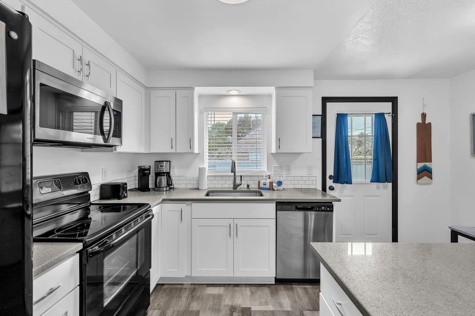 Step into your fully equipped kitchen with stainless steel appliances, sleek white cabinetry, and plenty of counter space for preparing meals during your stay.