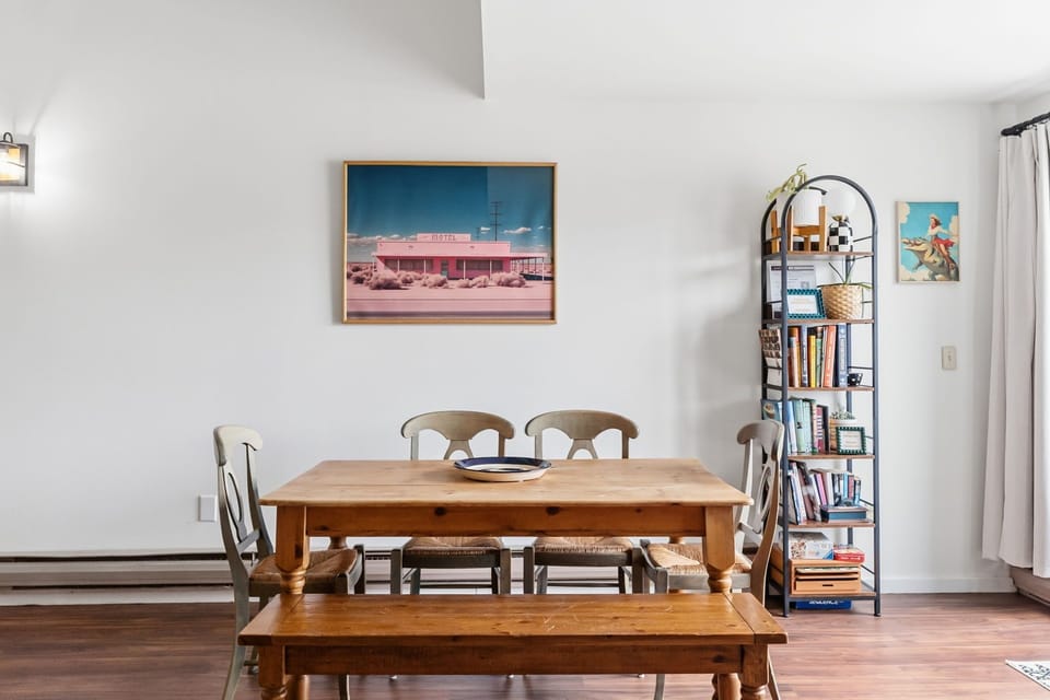 Gather around your warm wooden dining table with vintage desert artwork adorning the walls and books nearby for cozy evenings.