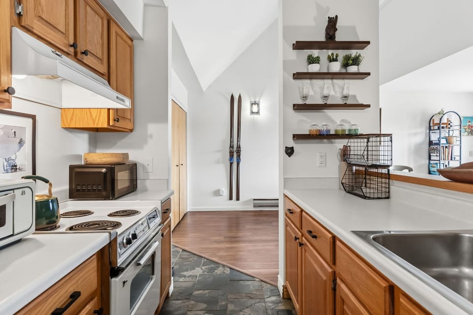 Your fully-equipped kitchen features warm wood cabinets, stainless appliances, and mountain-inspired touches like vintage skis on display.