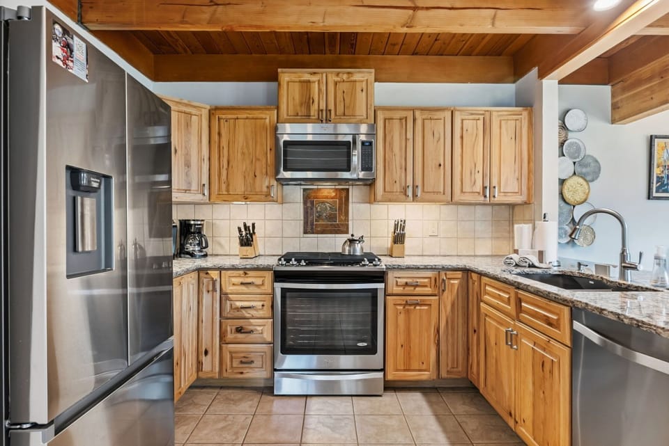 Your rustic-modern kitchen features warm wood cabinetry, granite countertops, and stainless steel appliances, perfect for preparing memorable meals during your stay.
