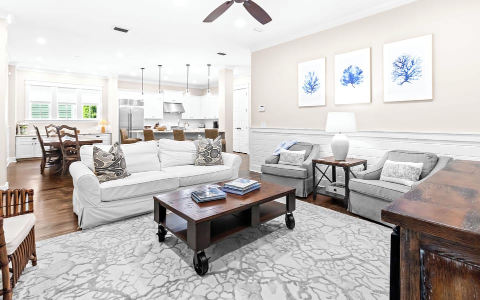 Step into your bright open living space where coastal elegance meets comfort. Sink into plush seating, enjoy the gentle breeze from your ceiling fan, and let the soft blue artwork transport you to relaxing beach days ahead.