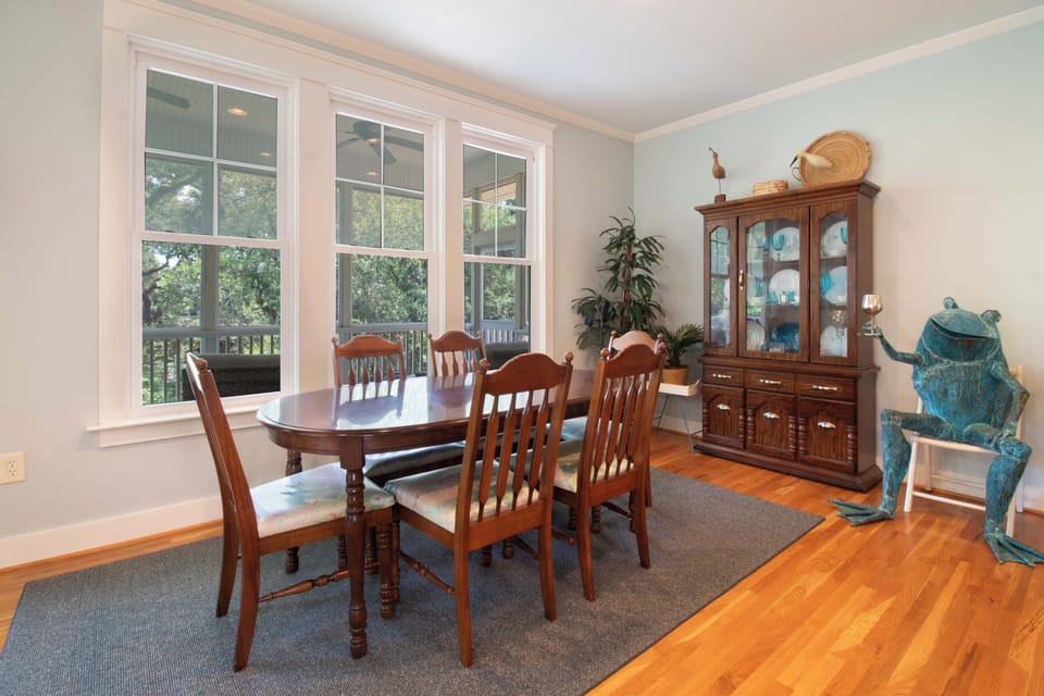 Your dining area awaits with warm wood tones and sunlit windows framing lush garden views—perfect for leisurely breakfasts or sharing meals with loved ones in this inviting, homey space.