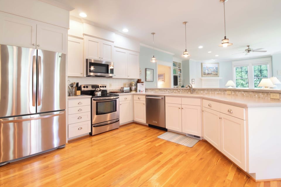 You'll love preparing meals in this bright, fully-equipped kitchen with gleaming stainless steel appliances, ample counter space, and warm hardwood floors throughout.