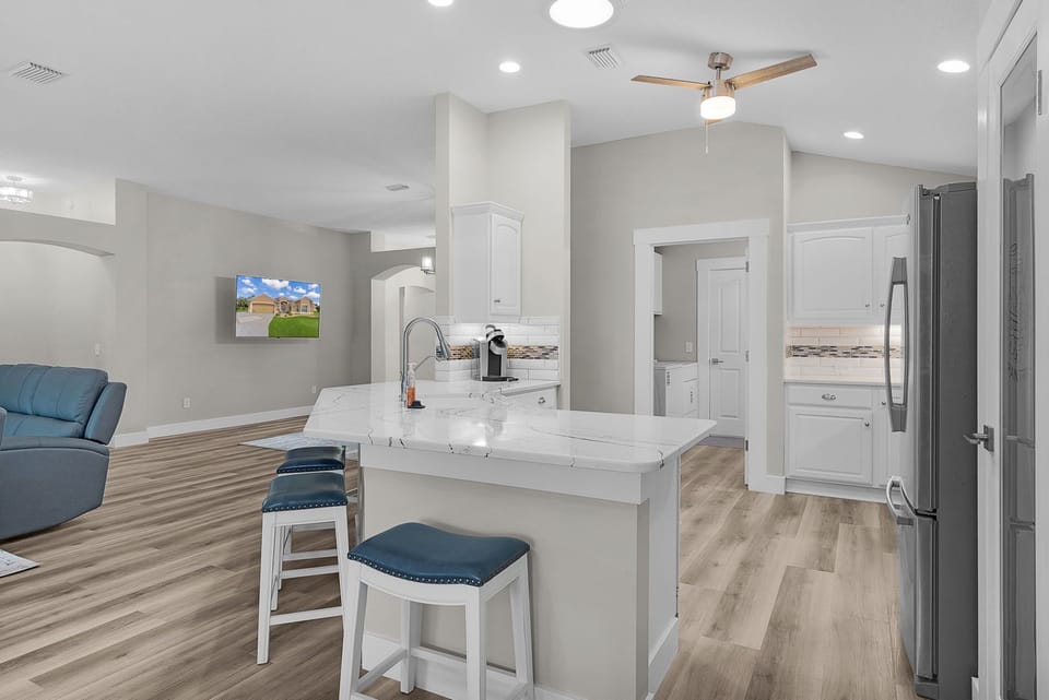 Gather around this sleek marble island for morning coffee or evening conversation, with modern appliances and bright, open-plan living flowing effortlessly around you.