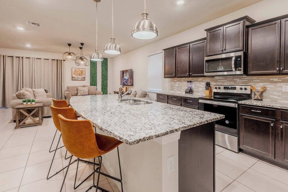 Experience a stylish kitchen with granite countertops and dark cabinetry, perfect for casual meals at the modern island. Enjoy the inviting ambiance created by warm lighting, ideal for gatherings with friends and family.
