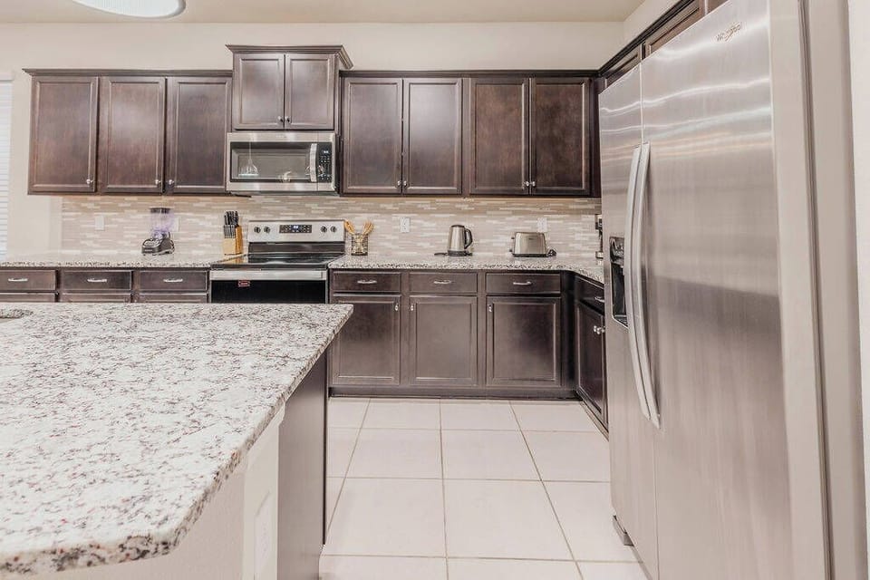 Welcome to this spacious kitchen with dark wooden cabinets and light granite countertops that create a stunning contrast. The sleek stainless steel appliances and open layout invite you to enjoy cooking and conversation with ease.