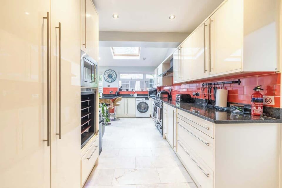 Long modern kitchen with glossy cabinets and bold red backsplash