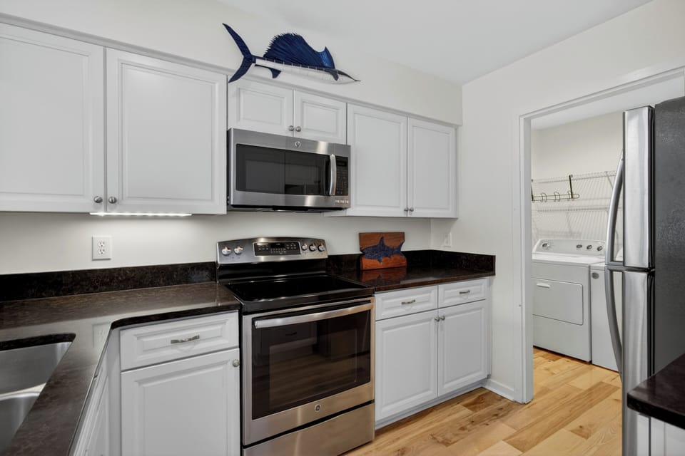 Your fully equipped kitchen features modern appliances and sleek countertops, with a convenient laundry room just steps away—everything you need for a comfortable, hassle-free stay.